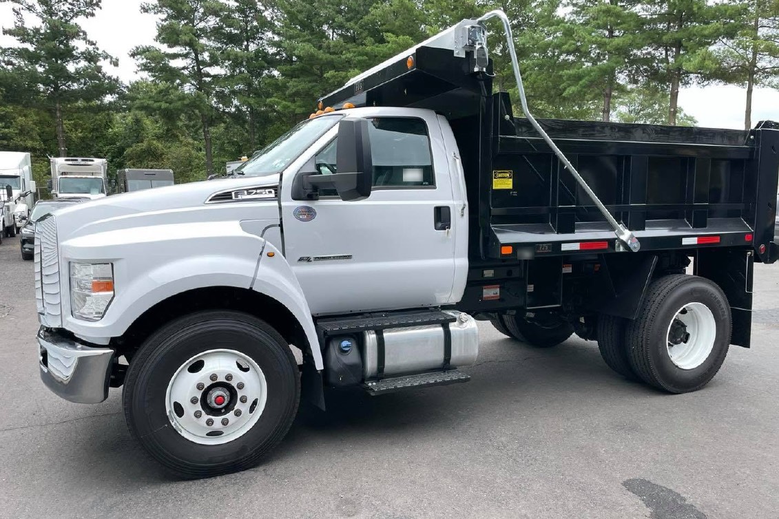 A white Ford F-750 dump truck parked on a lot, seen from the driver's side.
