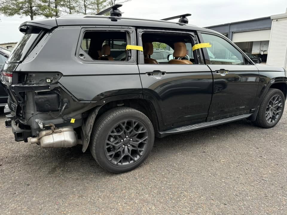 Jeep Grand Cherokee L partway through repair, with the rear bumper and tail lights off and the rear glass out.