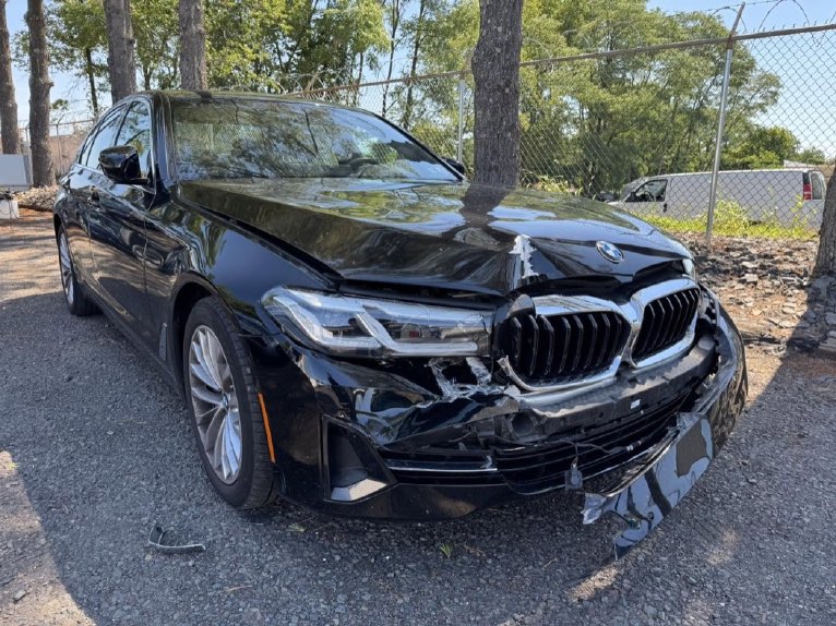 Black BMW 5 Series with the front bumper pulled away from the grille and the bumper cover split.