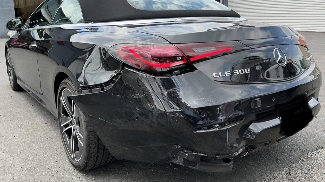 Black Mercedes CLE 300 with its rear bumper torn loose and the rear quarter panel creased.